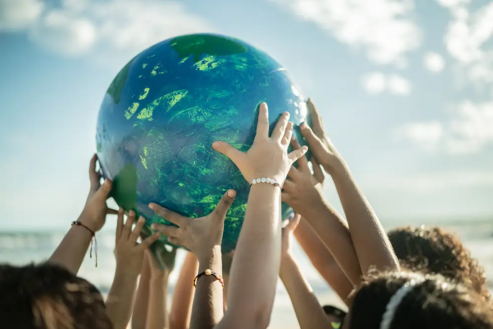 Close-up-of-children-holding-a-planet-at-the-beach-sustainability